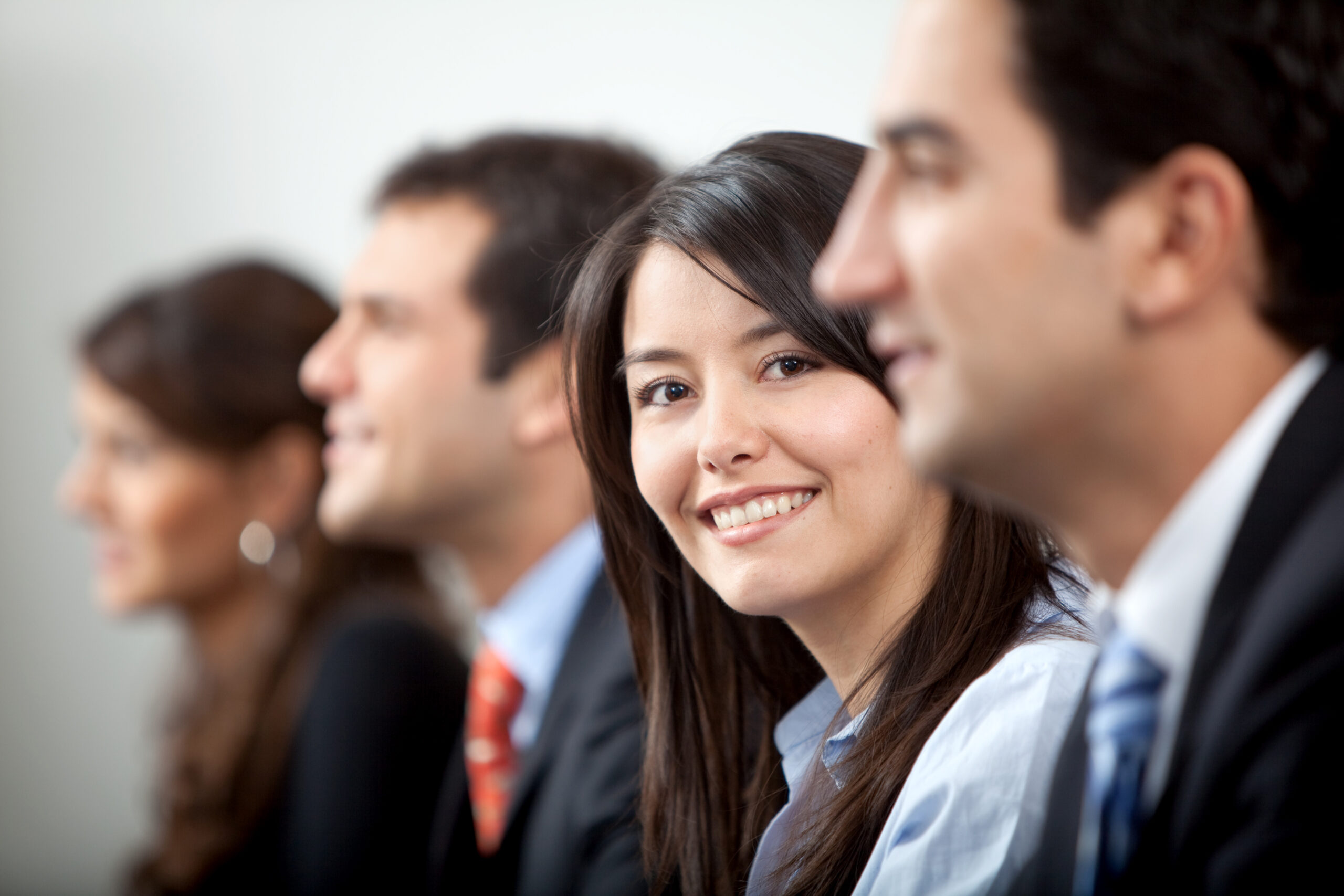 Happy woman awaiting job interview with others in business attire