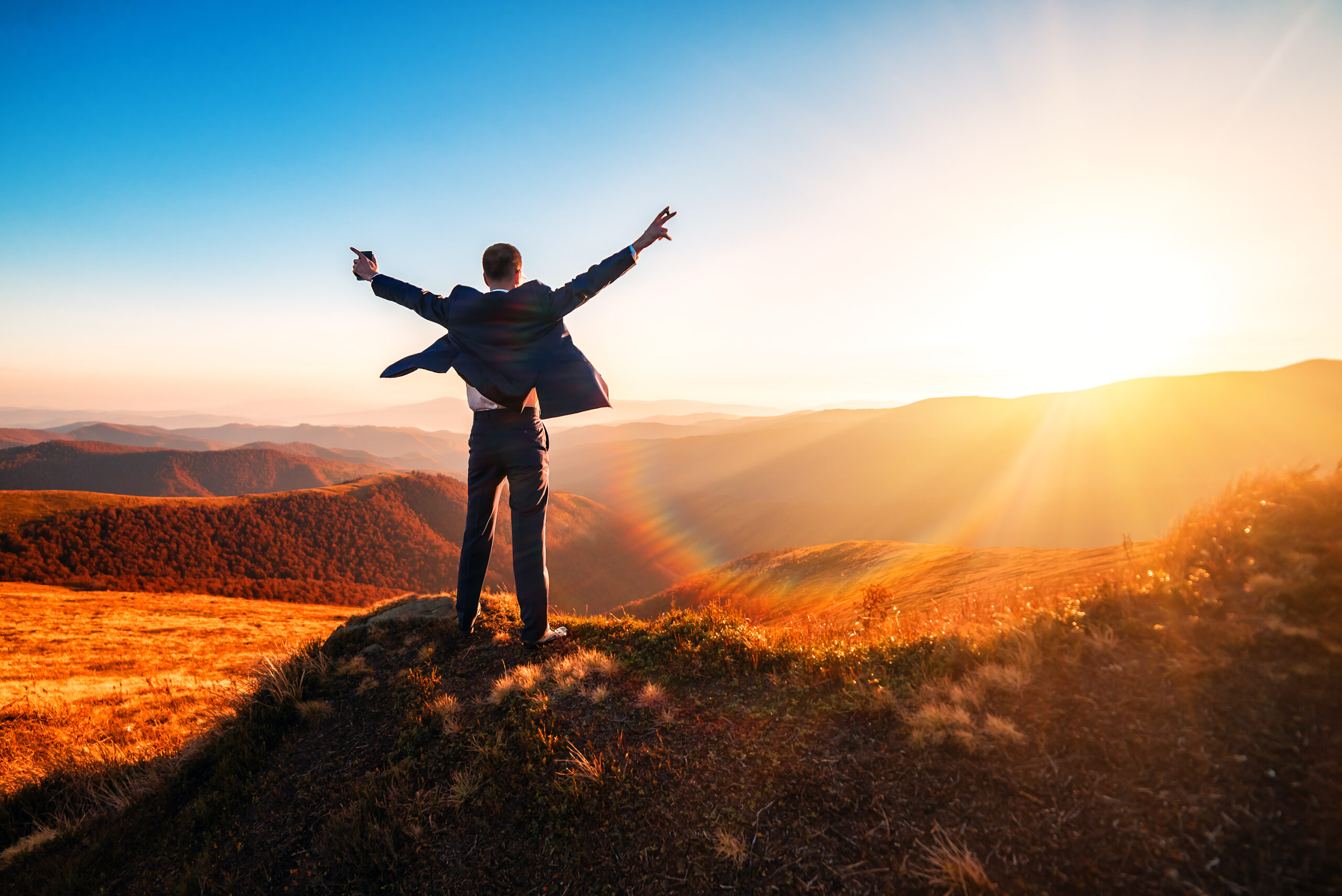 Successful business person celebrating in the rising sun.